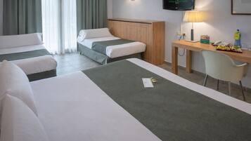 A hotel room with two beds, a desk with a chair, a TV, and a window with curtains.