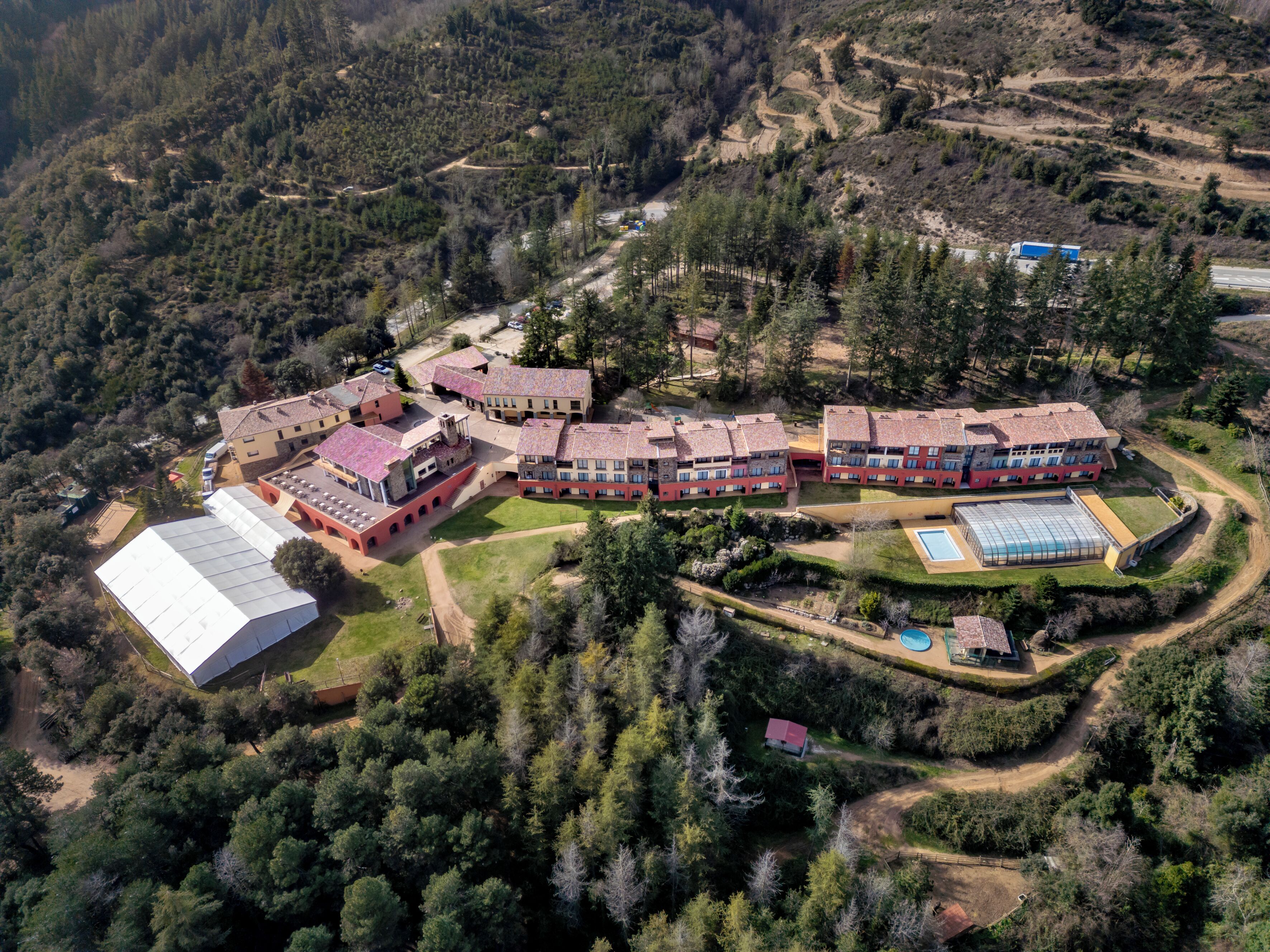 Ein Luftbild eines großen, mehrstöckigen Hotels mit Innenhof, umgeben von dichtem Wald.