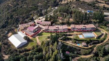 Ein Luftbild eines großen, mehrstöckigen Hotels mit Innenhof, umgeben von dichtem Wald.