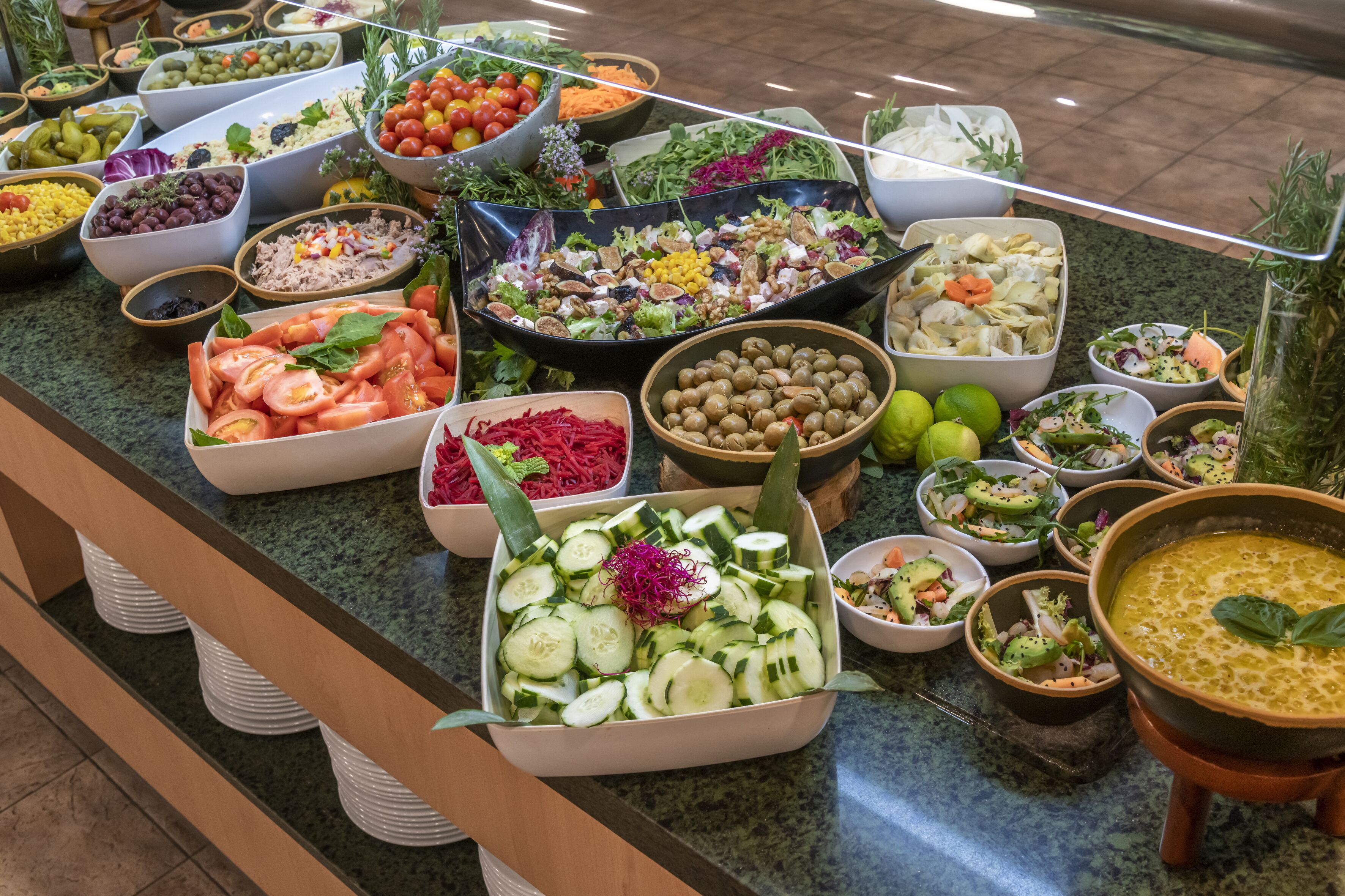 Un bufé con diferentes opciones de comida, como ensaladas, frutas y verduras.