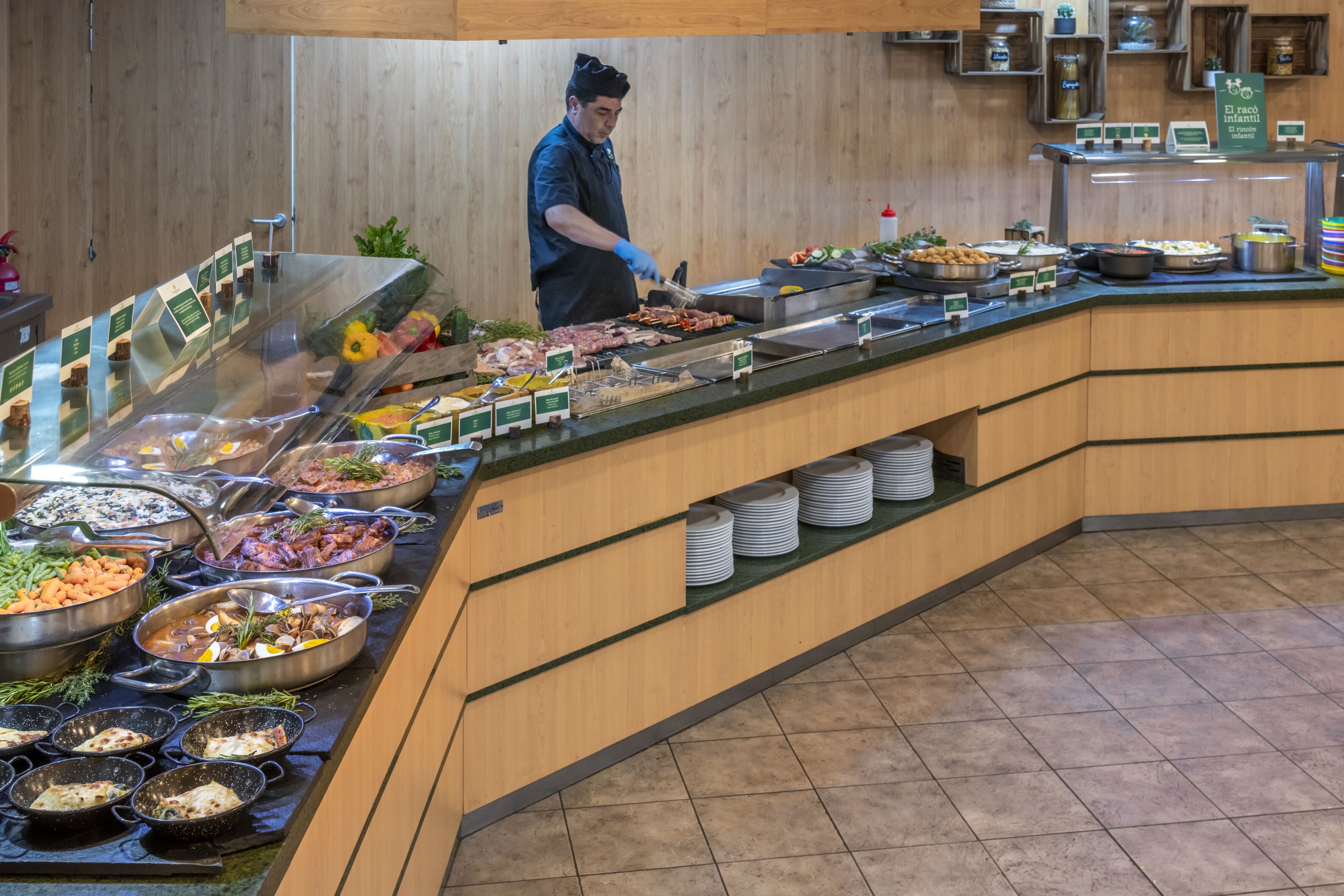 A buffet with various food items and a staff member serving.