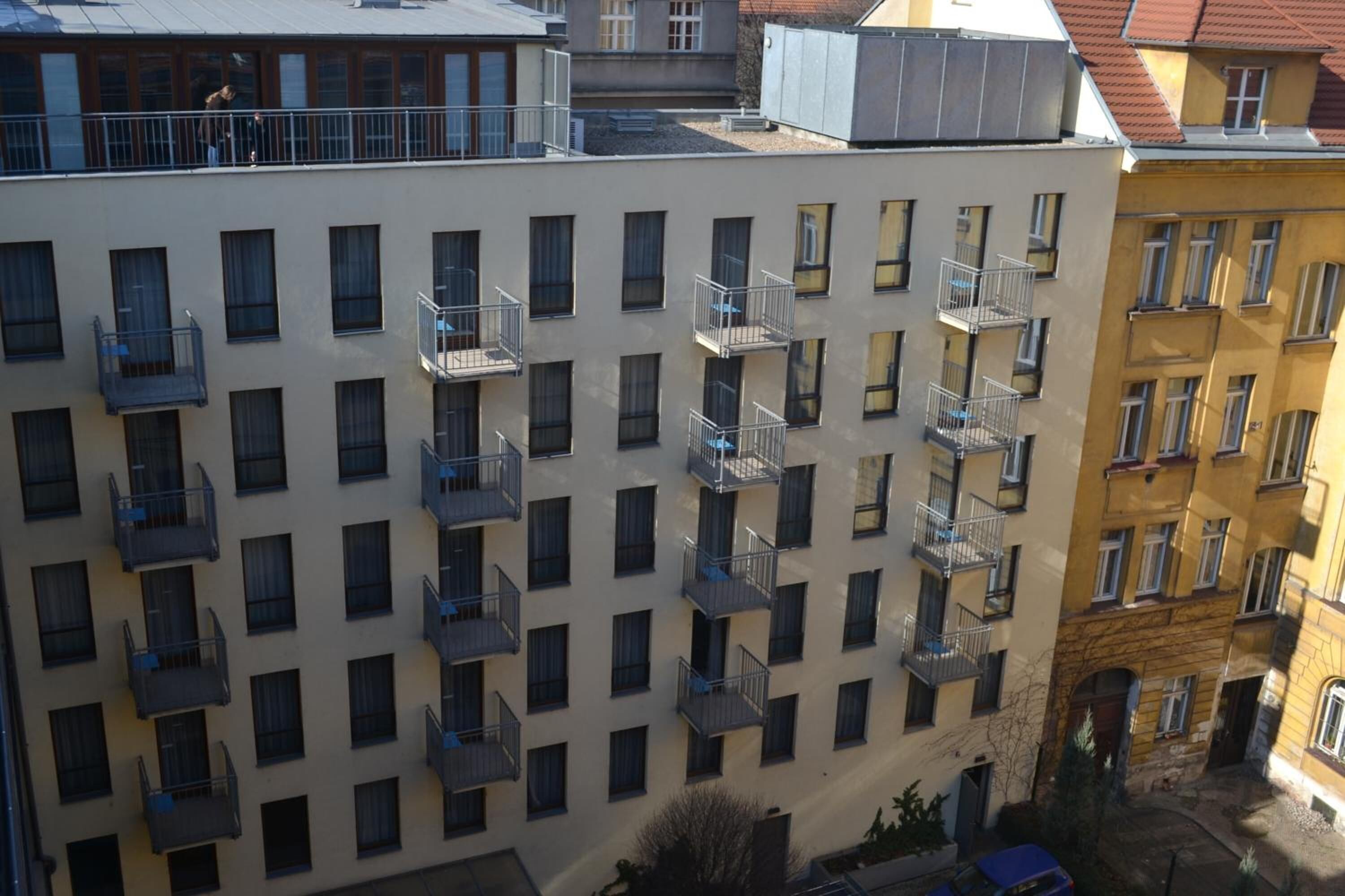 A multi-story building with balconies, a courtyard, and neighboring buildings.