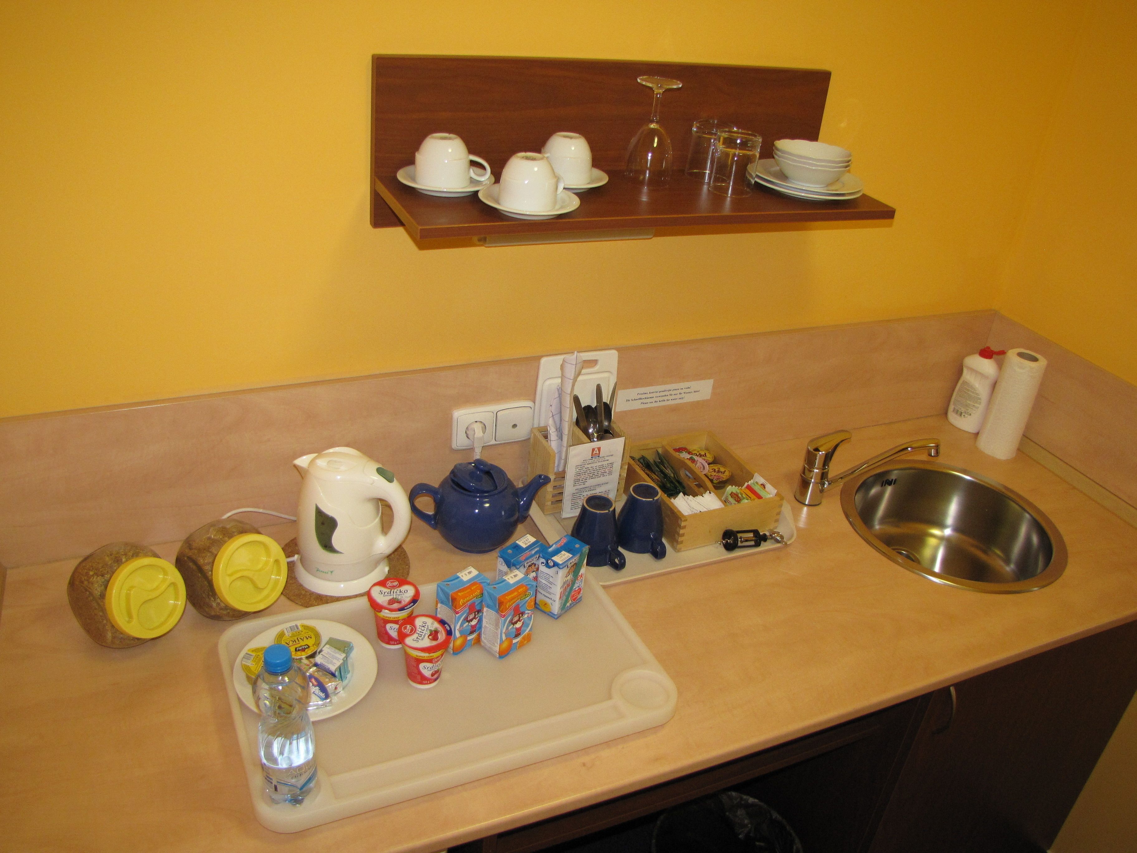 A kitchen counter with a sink, a coffee maker, a kettle, and various food items.