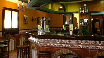 Zona de bar con salpicadero de azulejos, taburetes y una variedad de botellas en estanterías.