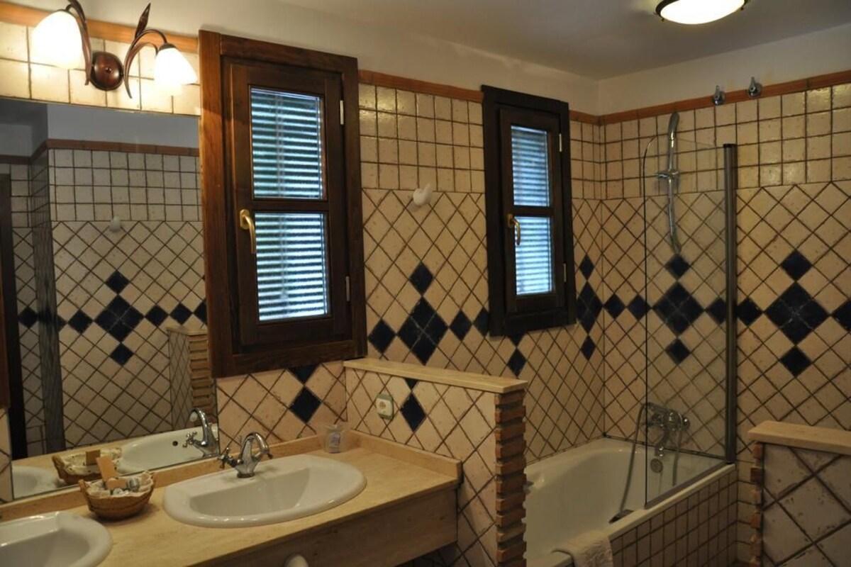 Een badkamer met twee wastafels, een bad en een douche.