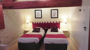 A room with two beds, wooden beams on the ceiling, two framed pictures on the wall, and bedside lamps.