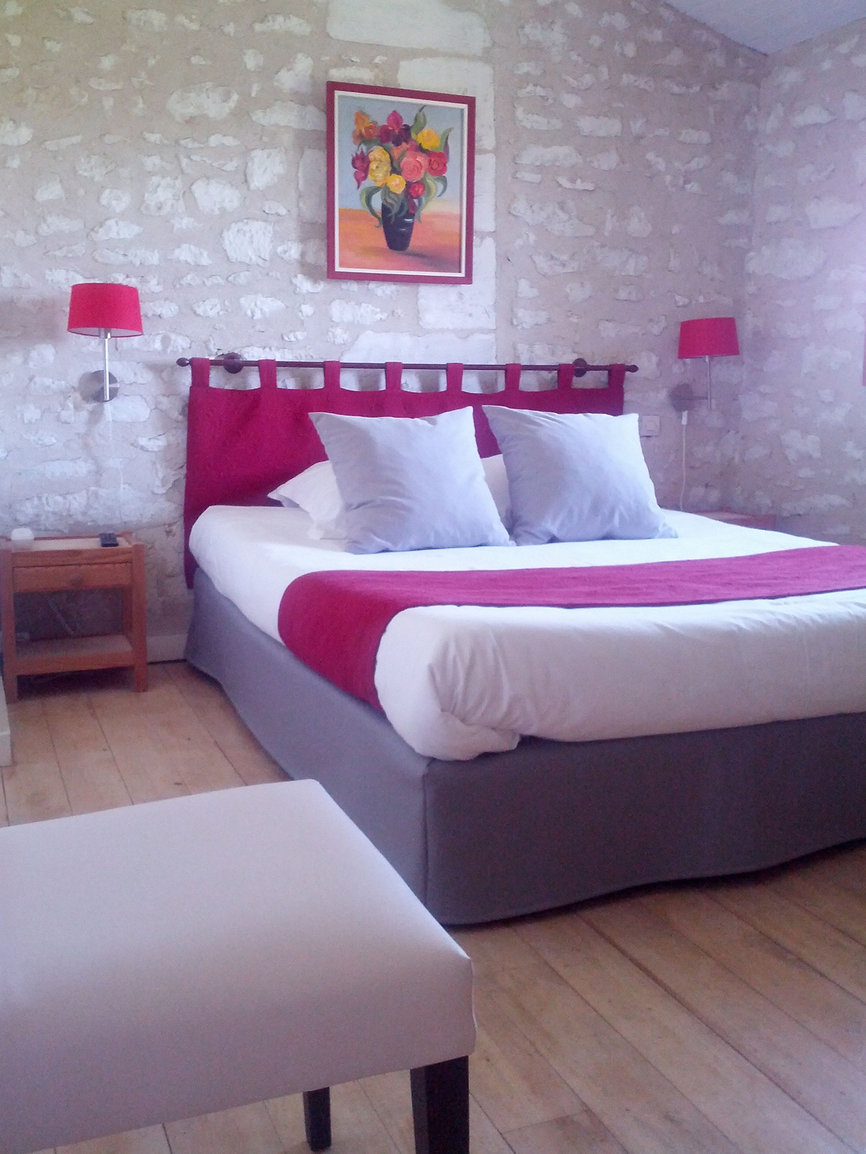 A bedroom with a bed, bedside tables, a nightstand, and a painting on the wall.