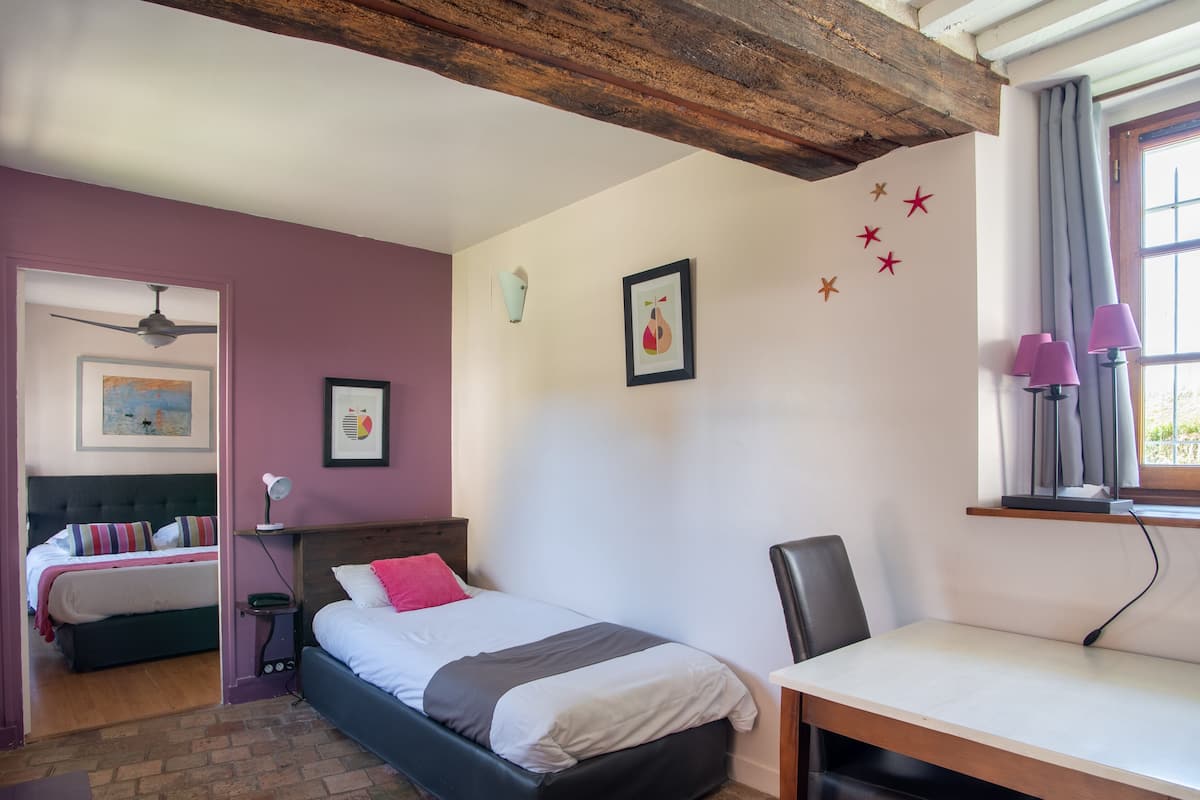 Un dormitorio con cama, escritorio, silla, radiador y ventilador de techo.