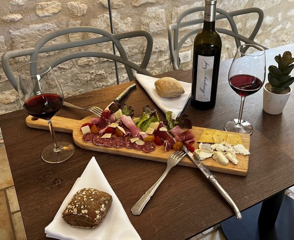 A wooden table with a charcuterie board, wine glasses, and a bottle of wine.