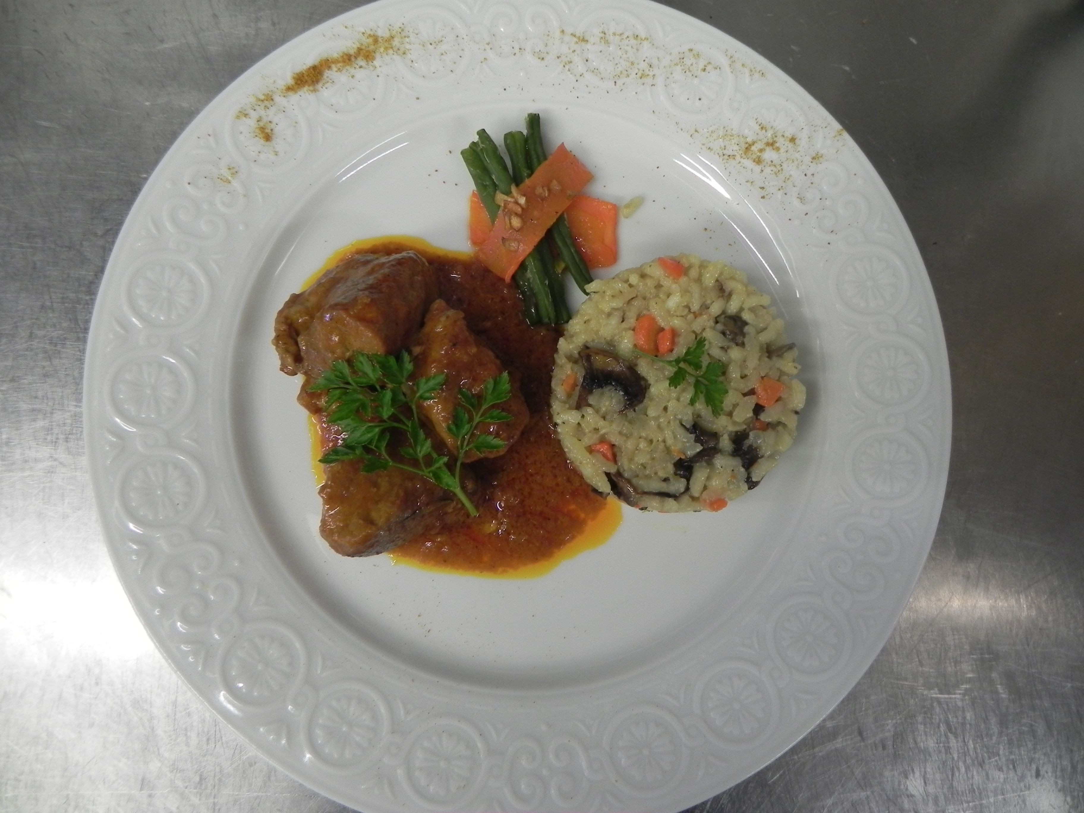 A plate with a meat dish, rice, and vegetables.