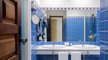 Un baño con azulejos azules, dos lavamanos, un espejo y una ducha.
