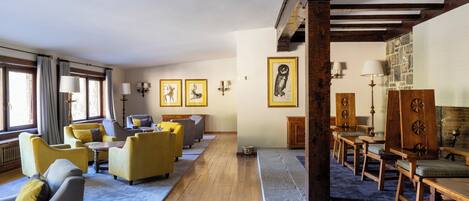 A hotel lobby with a long wooden bench, yellow armchairs, and a fireplace.