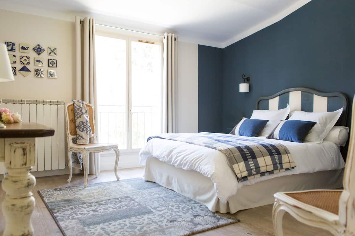 Une chambre à coucher avec un lit, une chaise, une table et une fenêtre avec des rideaux.