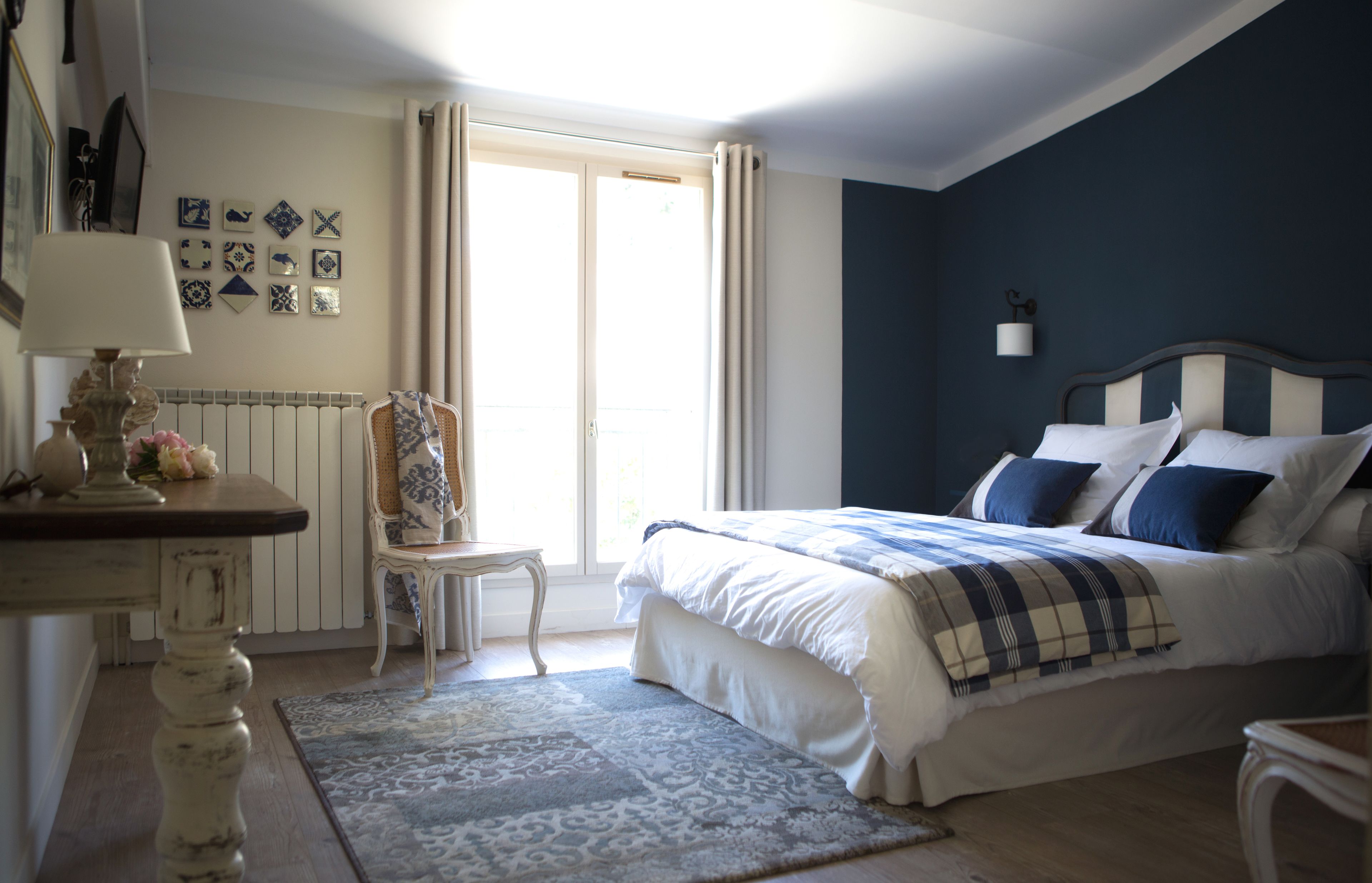 Een slaapkamer met een bed, een stoel, een tafel en een raam met gordijnen.