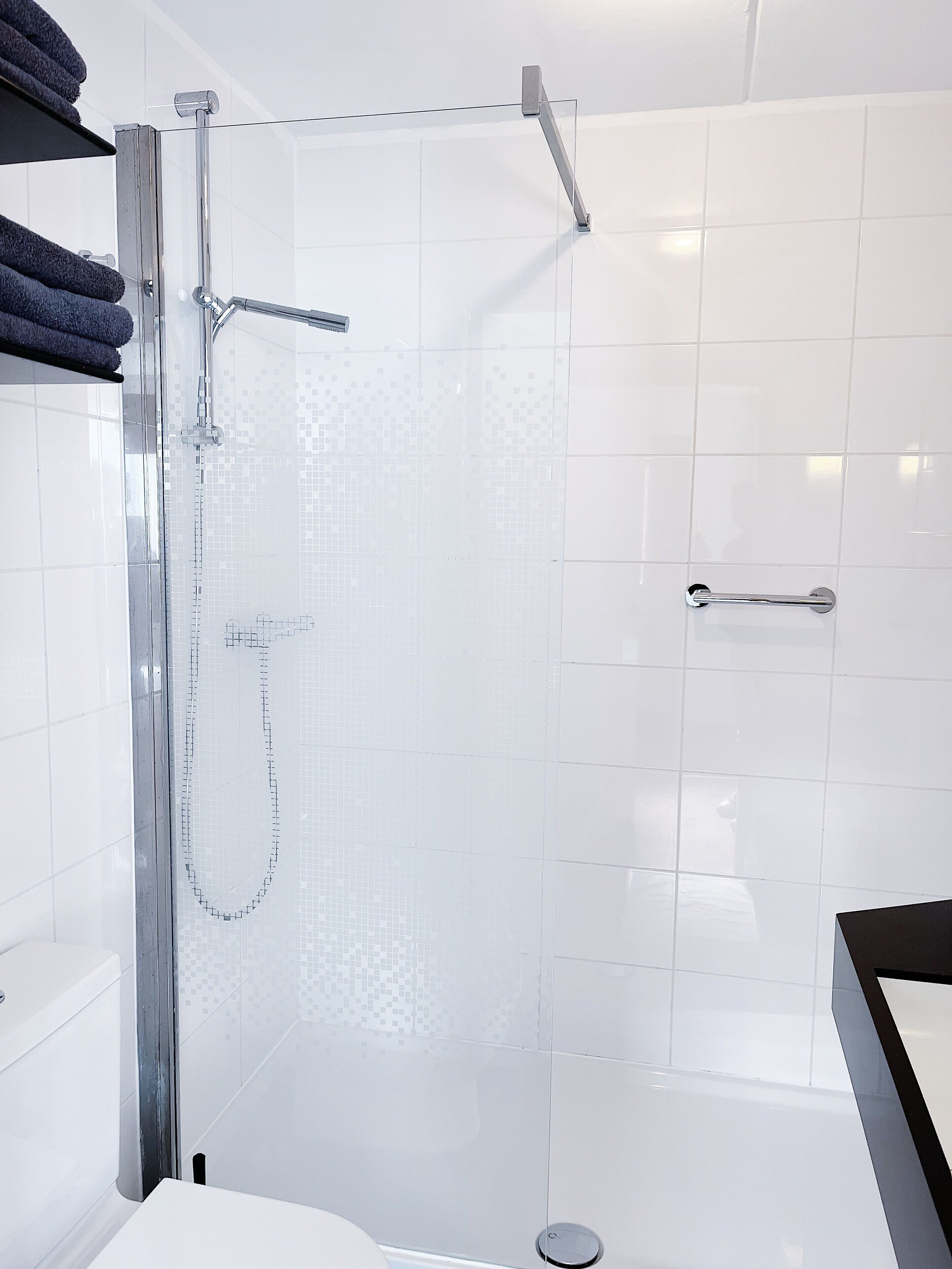 Un box de ducha moderno con puerta de cristal, grifería cromada y zona de ducha con azulejos.