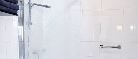 Un box de ducha moderno con puerta de cristal, grifería cromada y zona de ducha con azulejos.