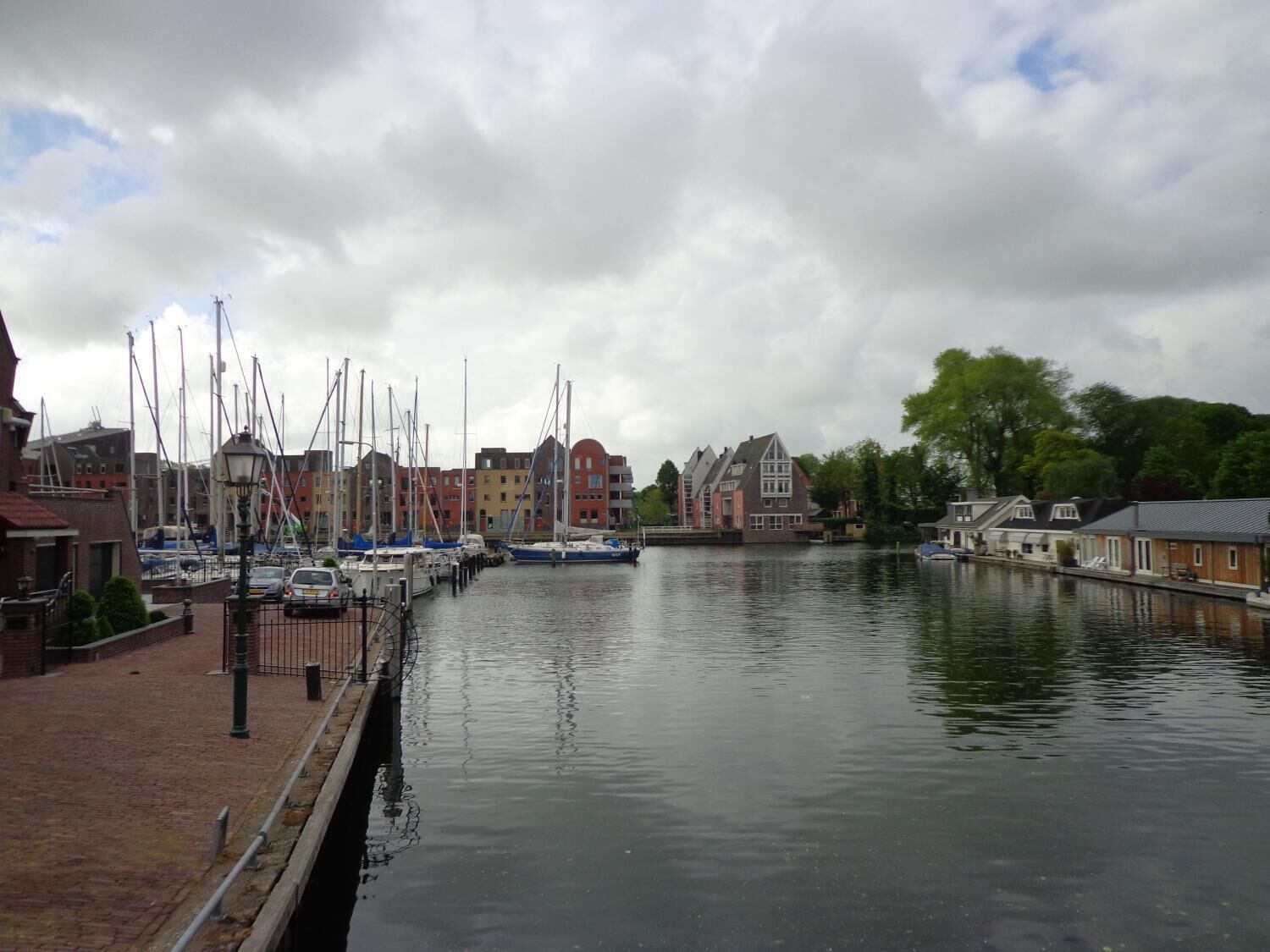 A canal with boats docked on the left, surrounded by buildings with red and white facades.