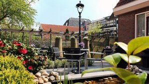 An outdoor patio with a small pond, seating area, and a street view in the background. - De Magneet (Hoorn)