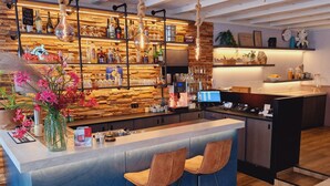 A modern bar area with a wooden backdrop, a bar counter, and two bar stools. - De Magneet (Hoorn)