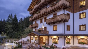 A multi-story building with wooden balconies, stone flooring, and outdoor seating areas. - Hotel Chalet del Sogno (Pinzolo)