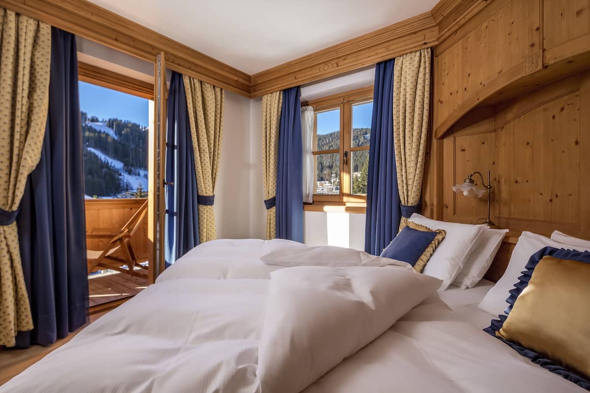 A bedroom with a large bed, wooden paneling, and a view of a snowy landscape through a window.