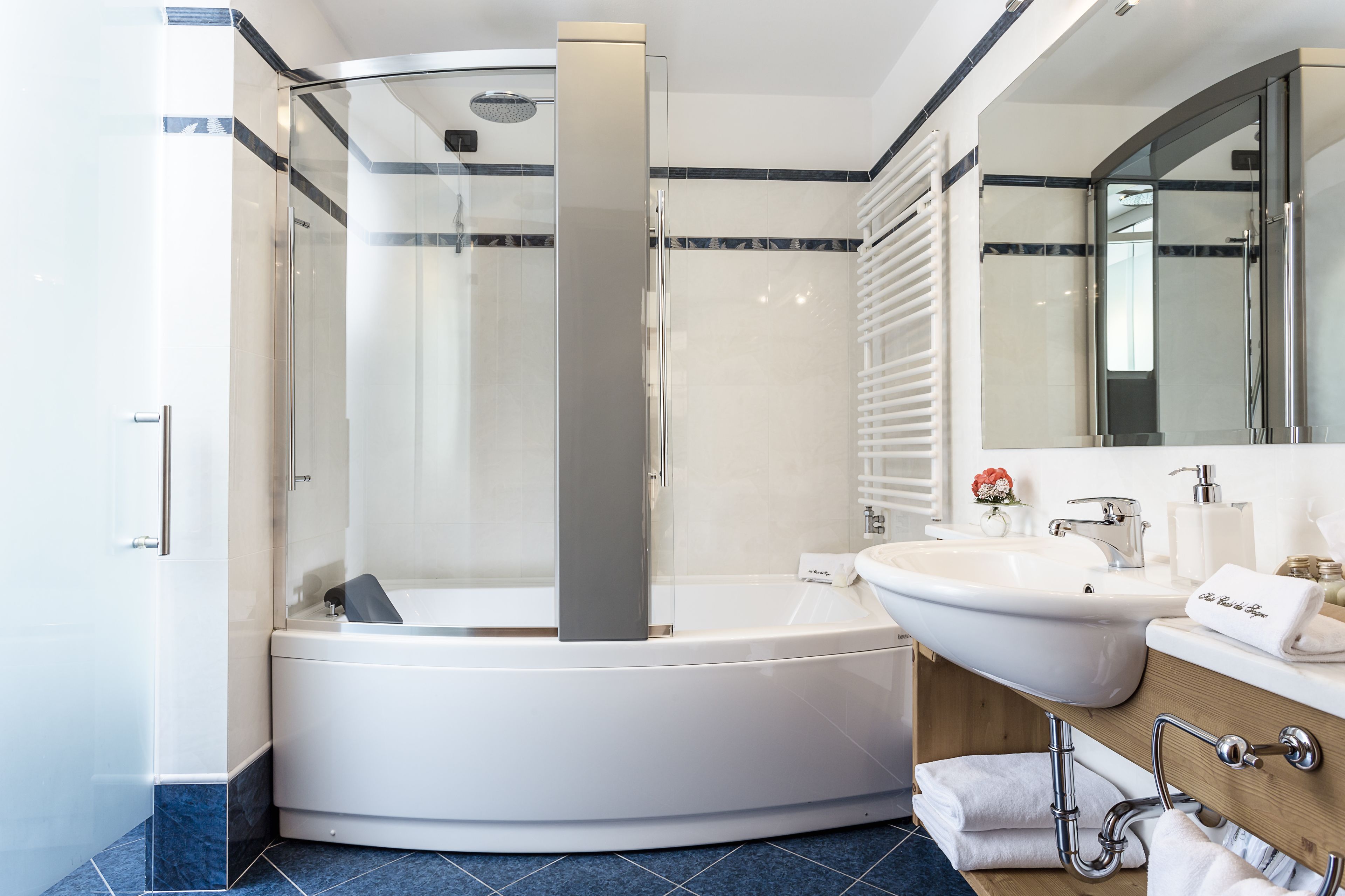 Un baño moderno con ducha de vidrio, una bañera independiente y un tocador con lavamanos y espejo.