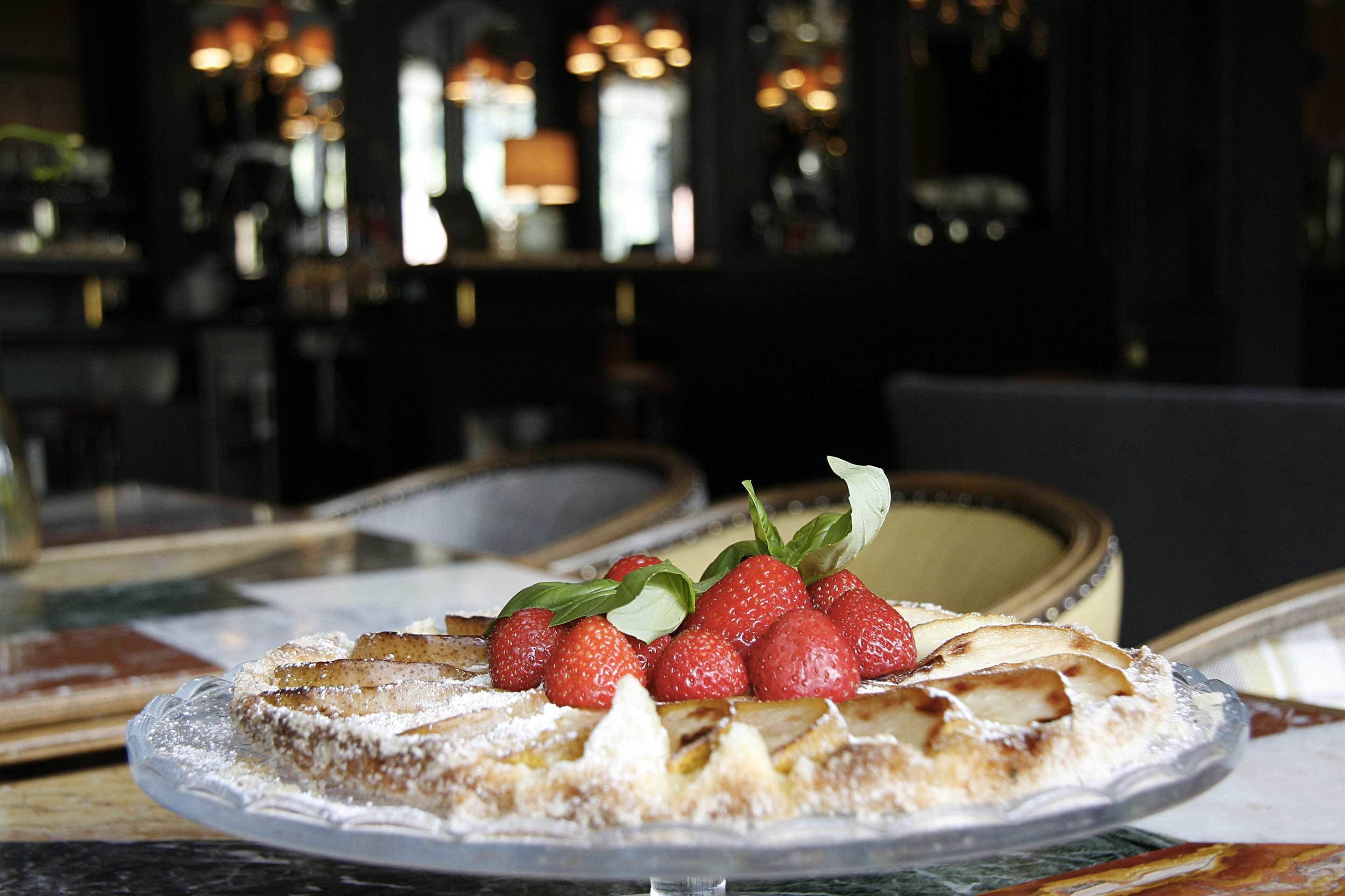 A dessert with strawberries and leaves on a clear glass plate.