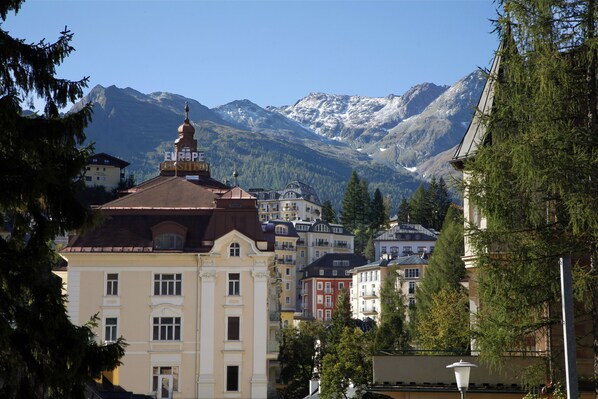 A town with historic buildings, a prominent church, and snow-capped mountains in the background.