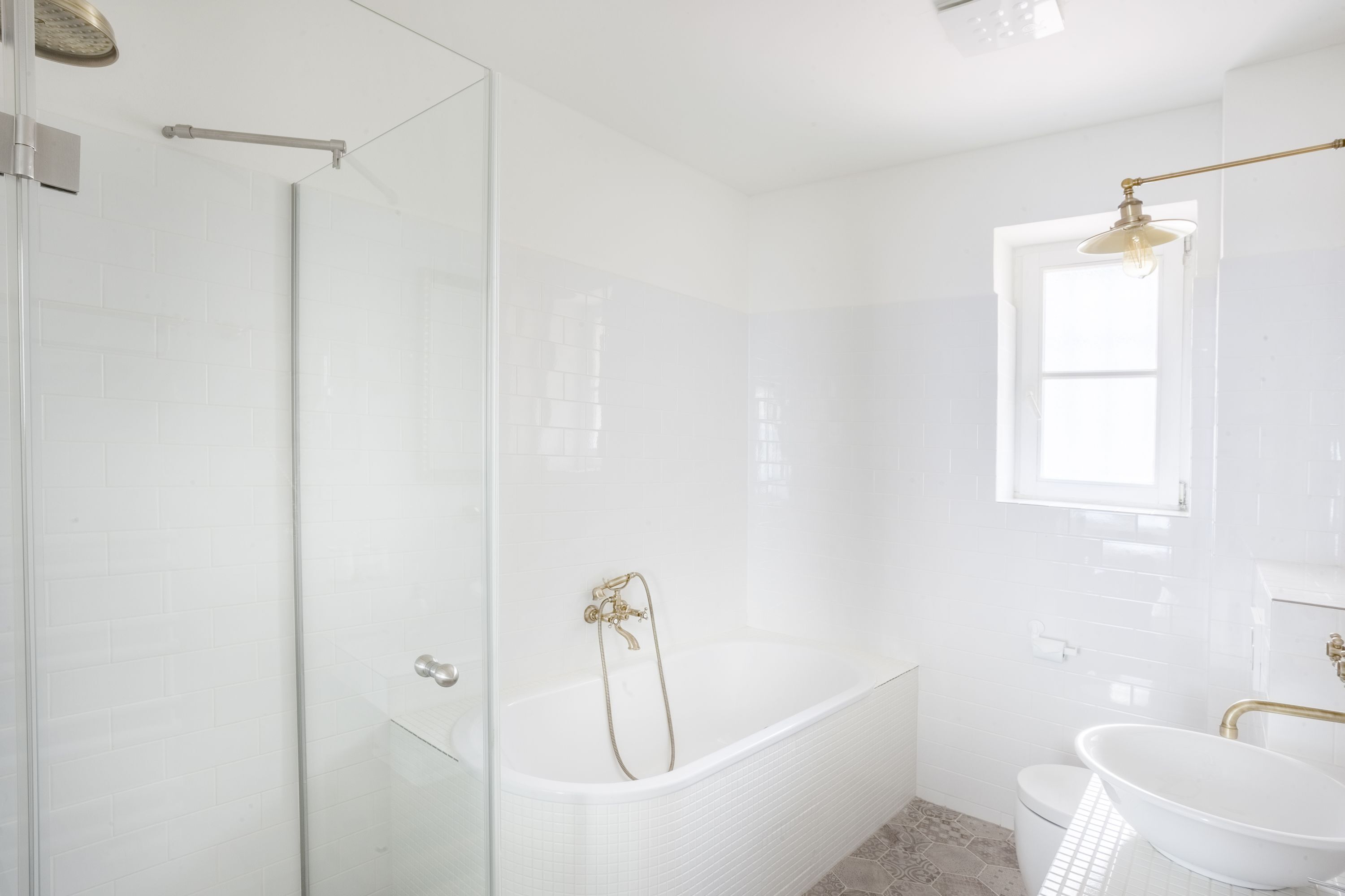 A modern bathroom with a glass shower enclosure, a freestanding bathtub, and a pedestal sink.