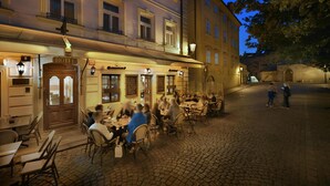 Een hotel met terras, een geplaveid straatje en klassieke architectuur.