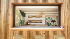 A wooden-framed window with a view of a bar area, including bottles and a shelf. - Les Jardins du Canal (Aigues-Mortes)