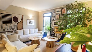 A living room with a sofa, two round tables, and a large plant. - Les Jardins du Canal (Aigues-Mortes)