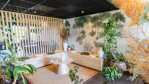 A modern interior with a wooden partition, a round table, and various potted plants. - Les Jardins du Canal (Aigues-Mortes)