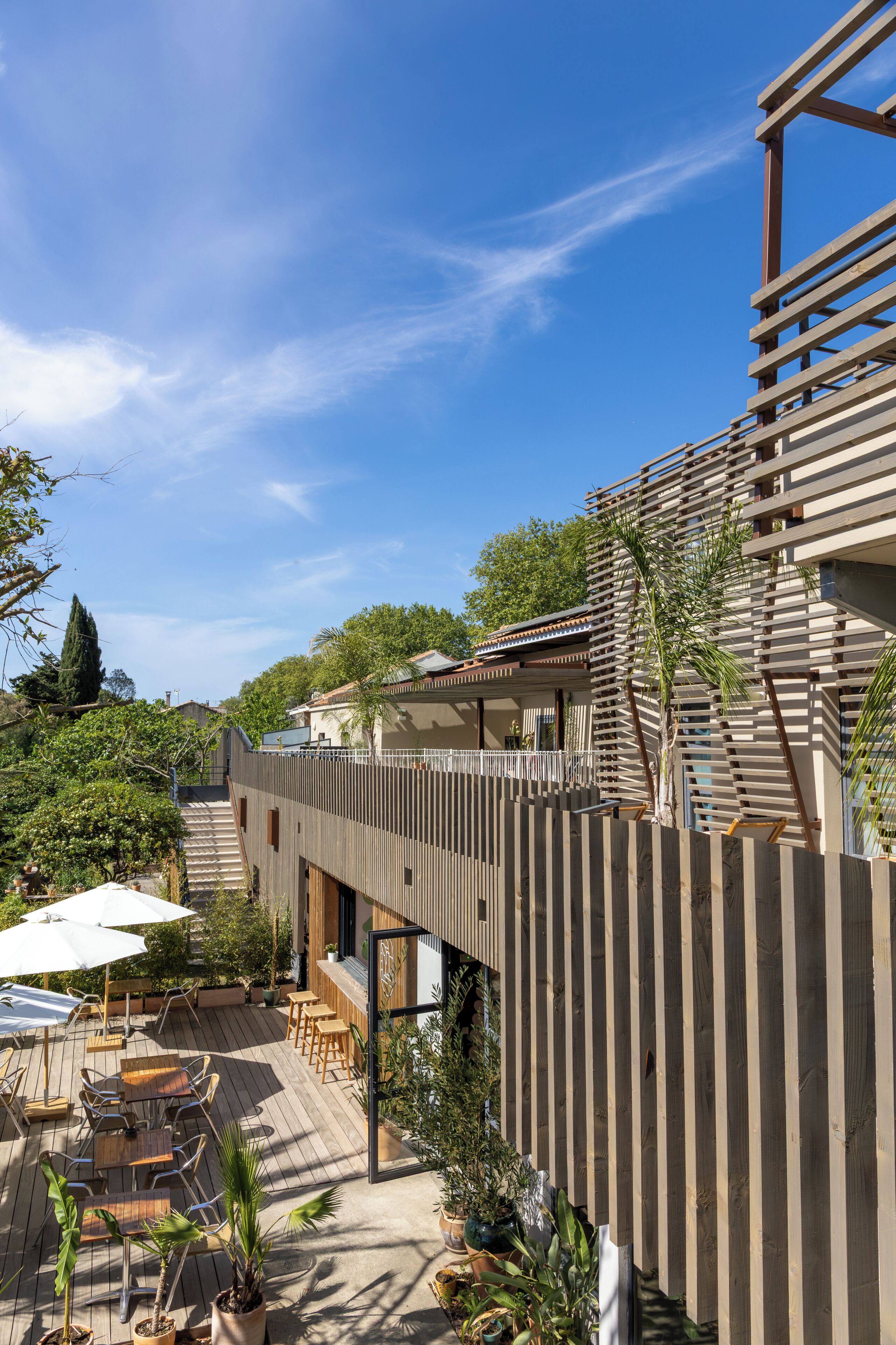 Un patio moderno al aire libre con mobiliario de madera y plantas en macetas.