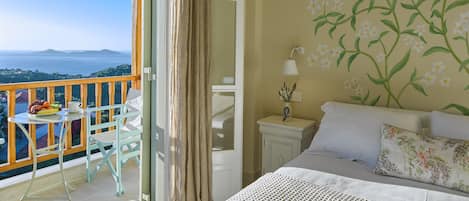 A bedroom with a balcony, a bed with white bedding, a nightstand with a lamp, and a floral wall mural.