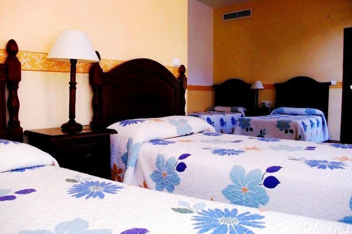 A hotel room with two beds, wooden headboards, and a nightstand with a lamp.
