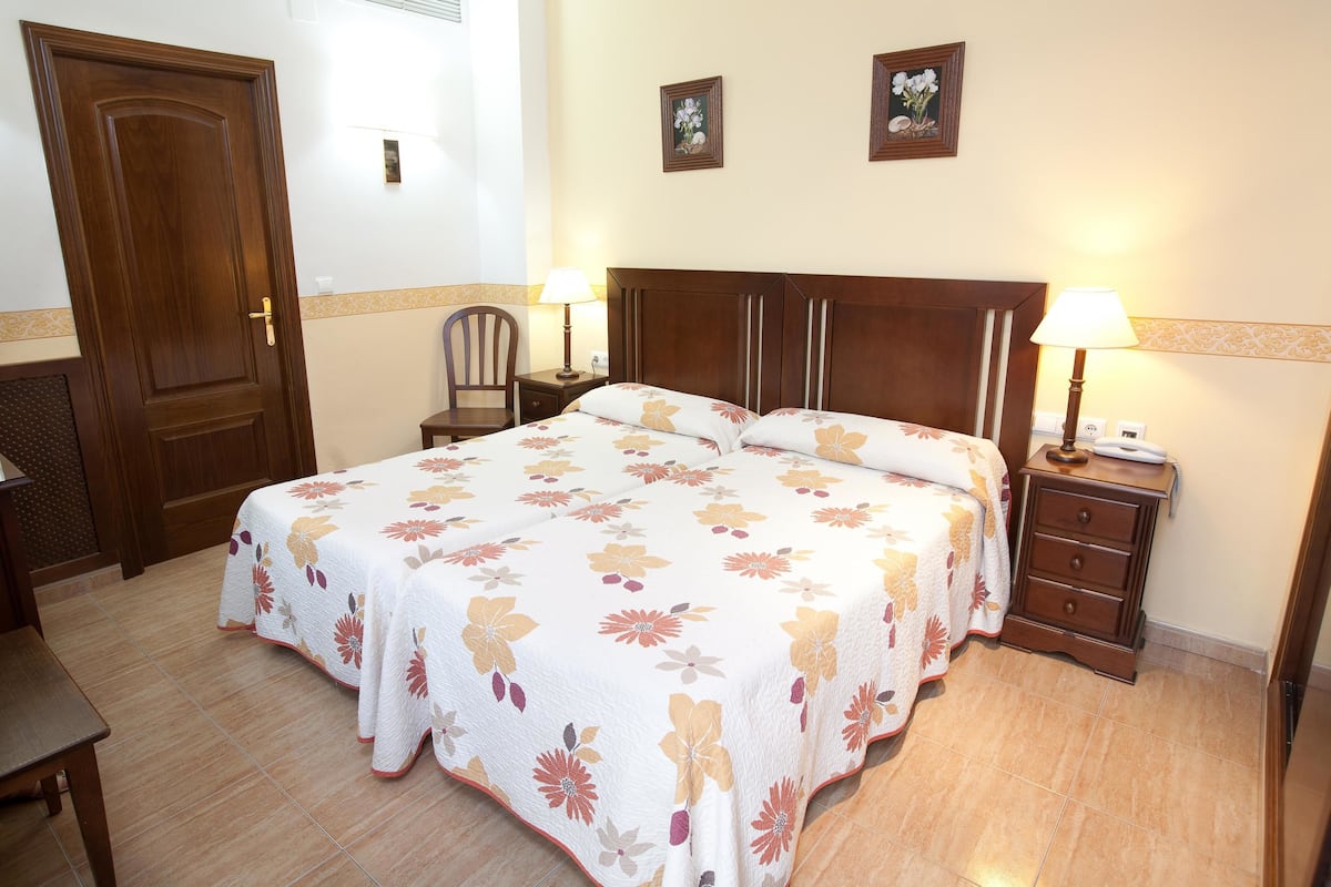 A bedroom with a large bed, two bedside tables with lamps, a wooden door, and a chair.
