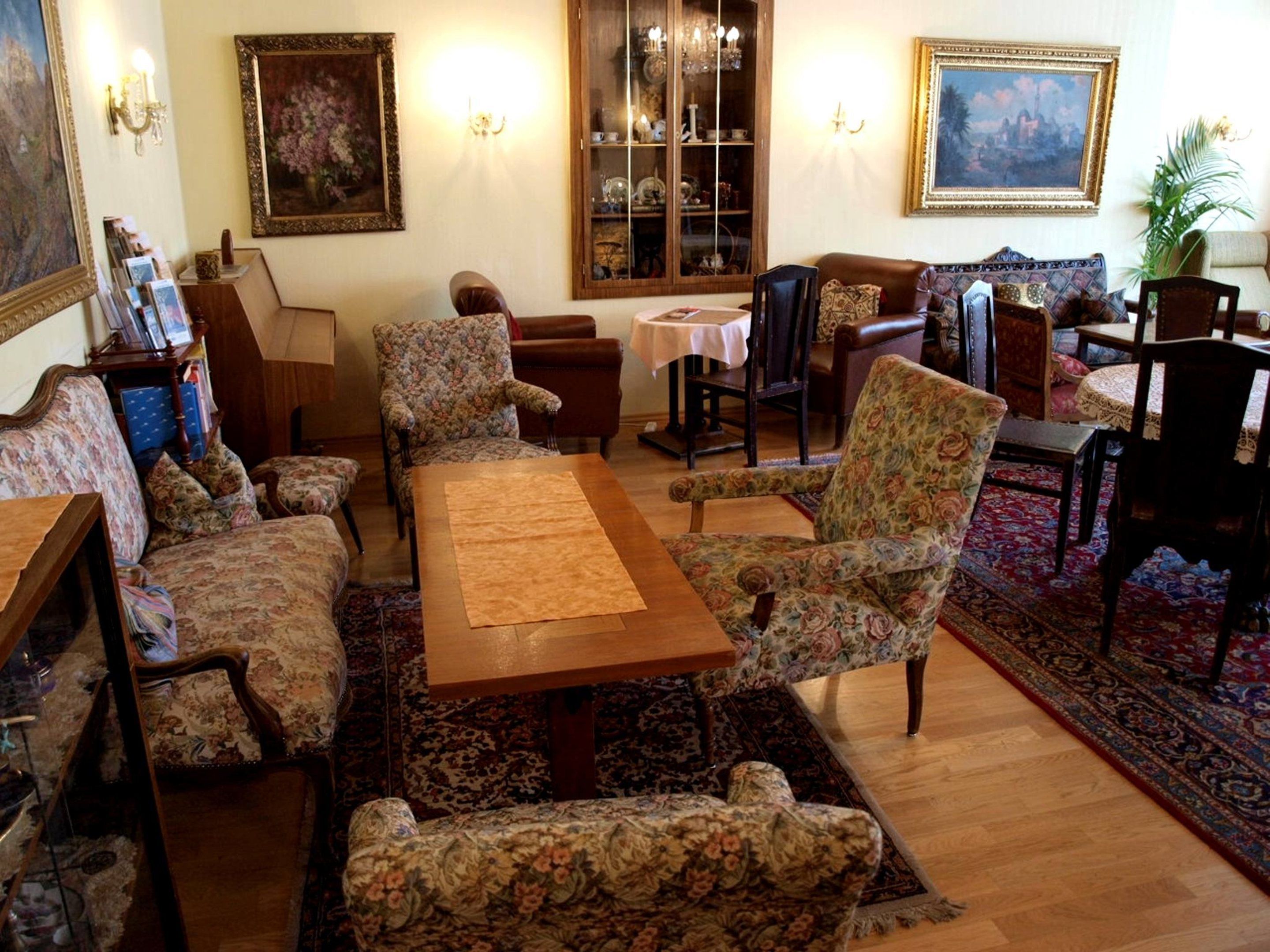 Uma sala de estar tradicional com sofás de padrão floral, uma mesa de centro de madeira e um espaço de jantar com mesa e cadeiras.