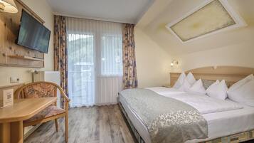 A hotel room with a bed, a desk, a chair, a television, and a window with curtains.