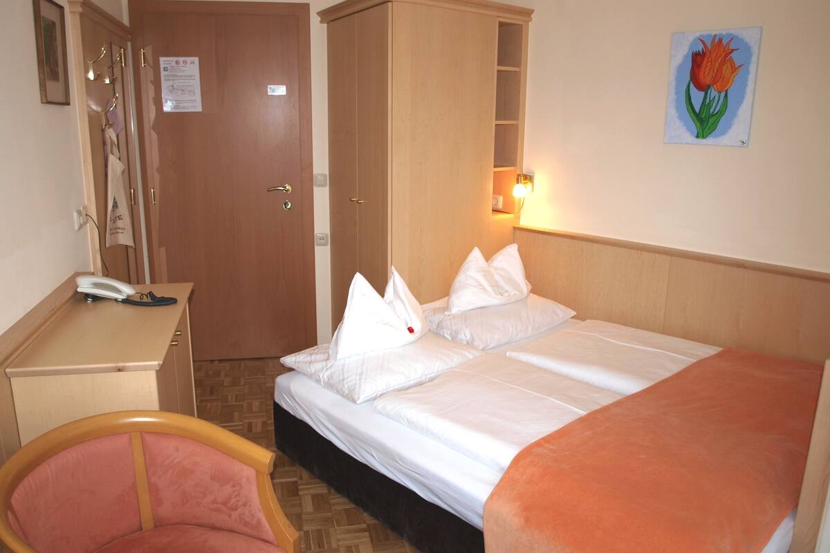 Ein Hotelzimmer mit Bett, Schreibtisch, Stuhl und einem Bild an der Wand.
