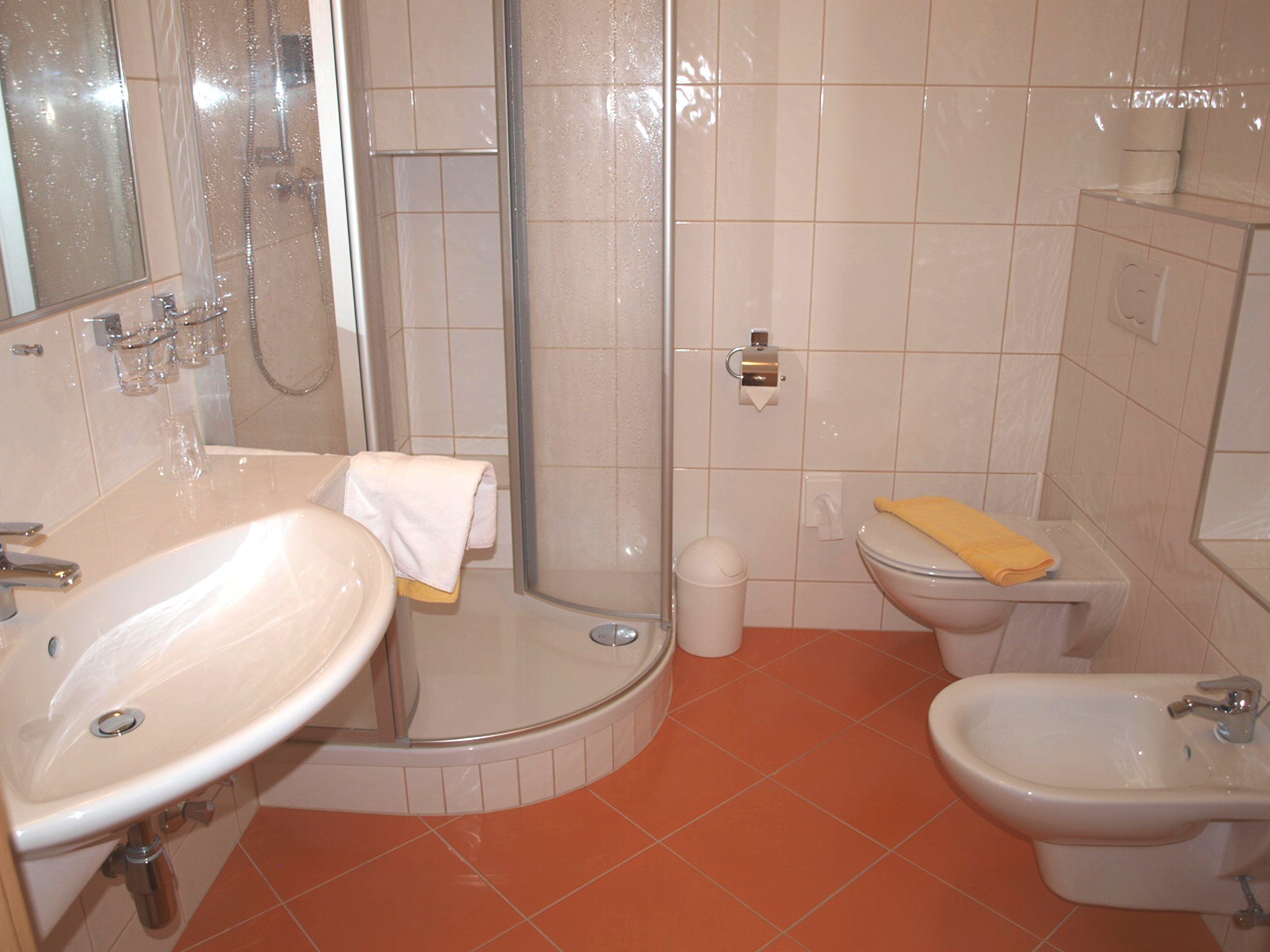 Un baño con lavamanos, inodoro, bidé y ducha.