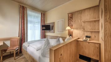 A hotel room with a bed, a desk, a chair, a TV, and a wooden cabinet.