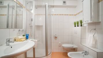 Un baño moderno con ducha envuelta en vidrio, un lavamanos, un inodoro y un bidé.