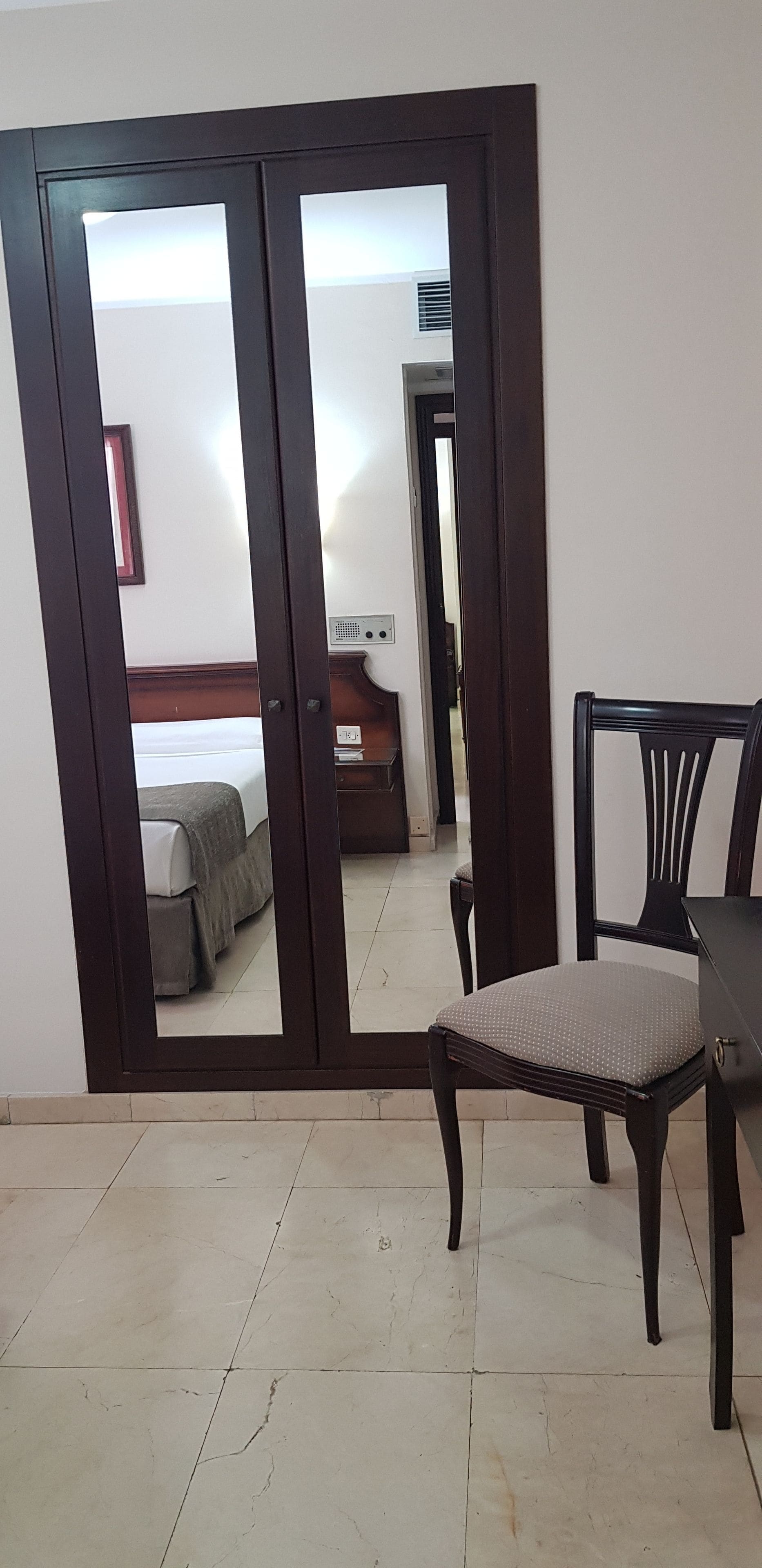A room with a sliding door leading to a bedroom, a chair, and a small table.