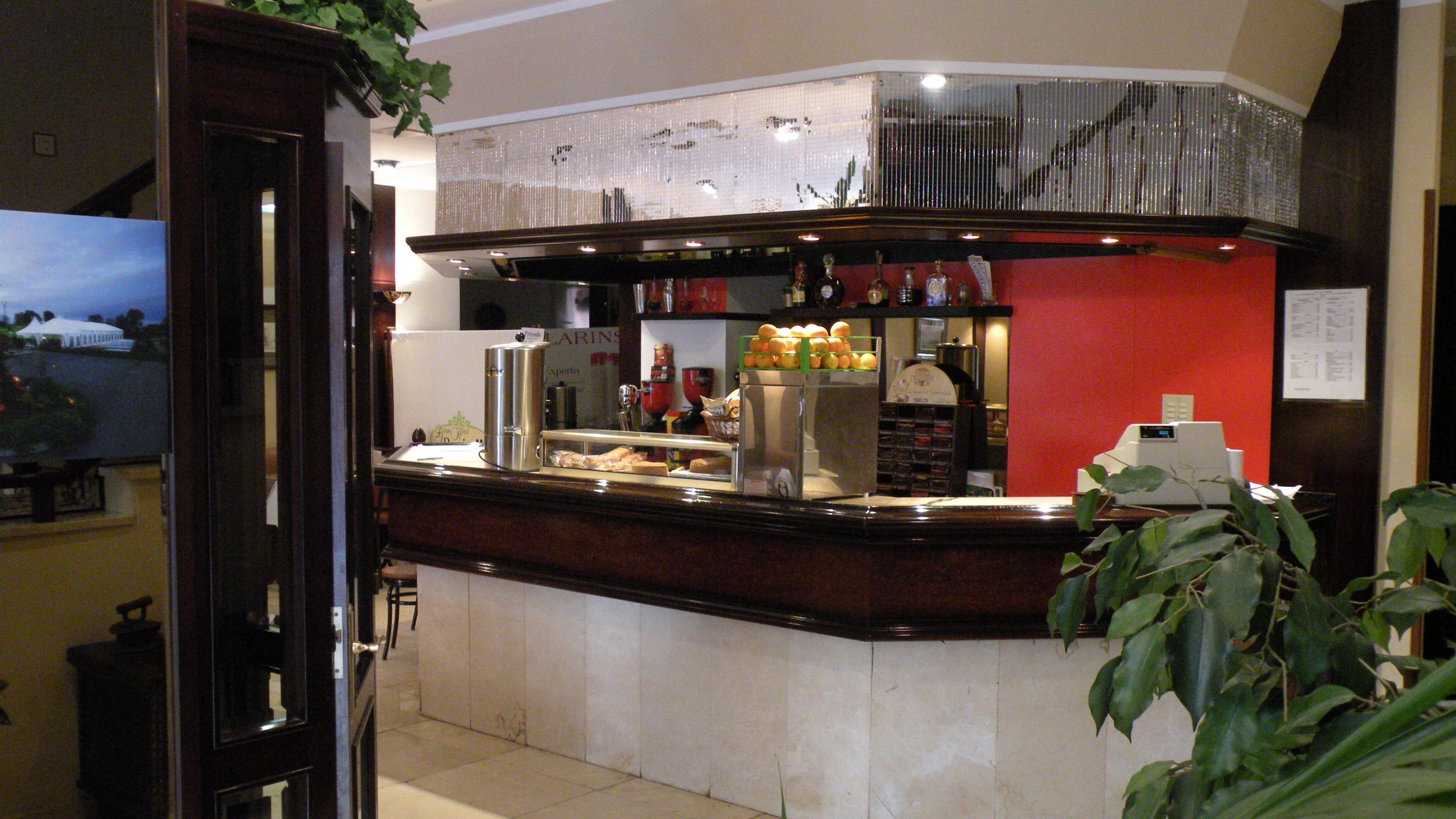 A bar area with a counter, a refrigerator stocked with beverages, and a display of fruits.