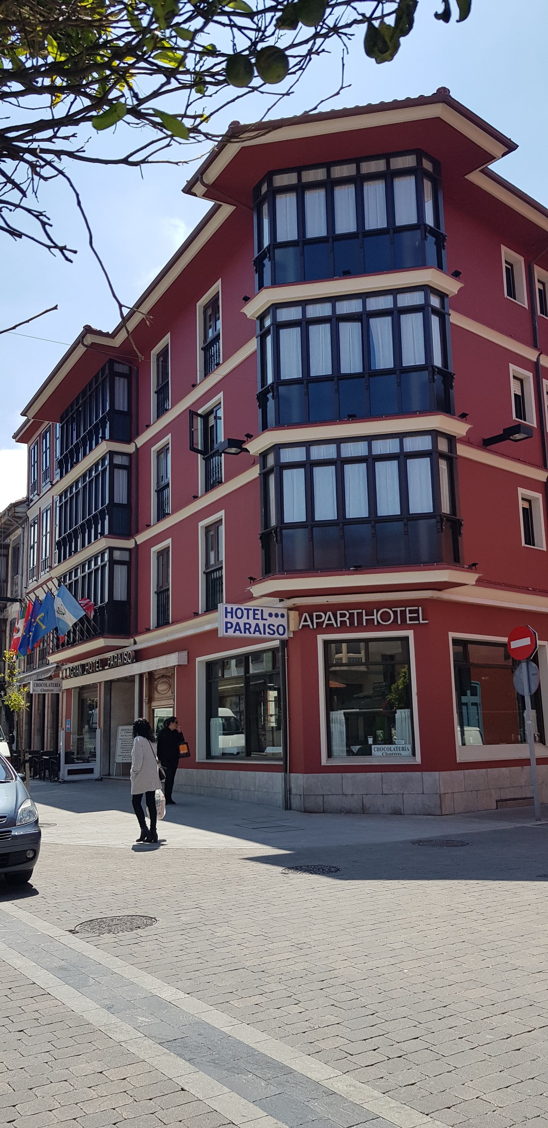 A red building with a sign that reads "HOTEL...APARTHOTEL" and "CHOCOLATERIA CHARTER".