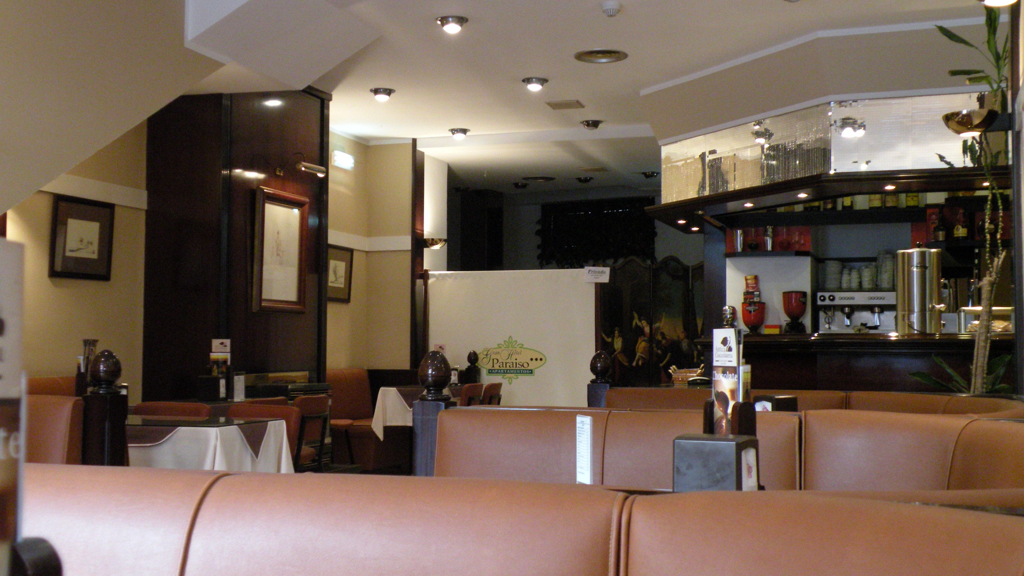 Un restaurante con cabinas de cuero, una zona de bar con una máquina de café y obras de arte enmarcadas en las paredes.