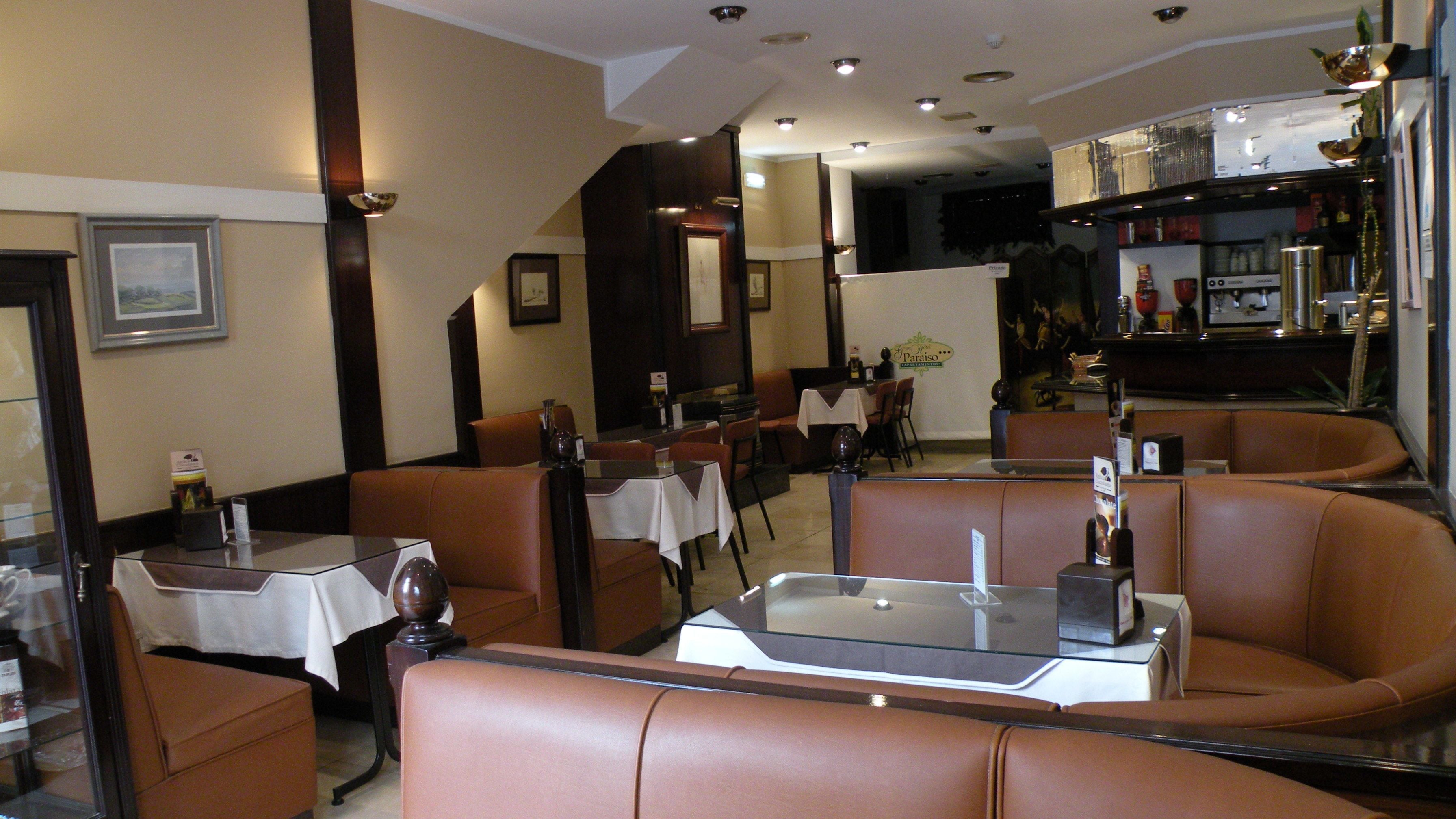 Een restaurantinterieur met zitplaatsen in cabines en tafels, een bar en een balie.