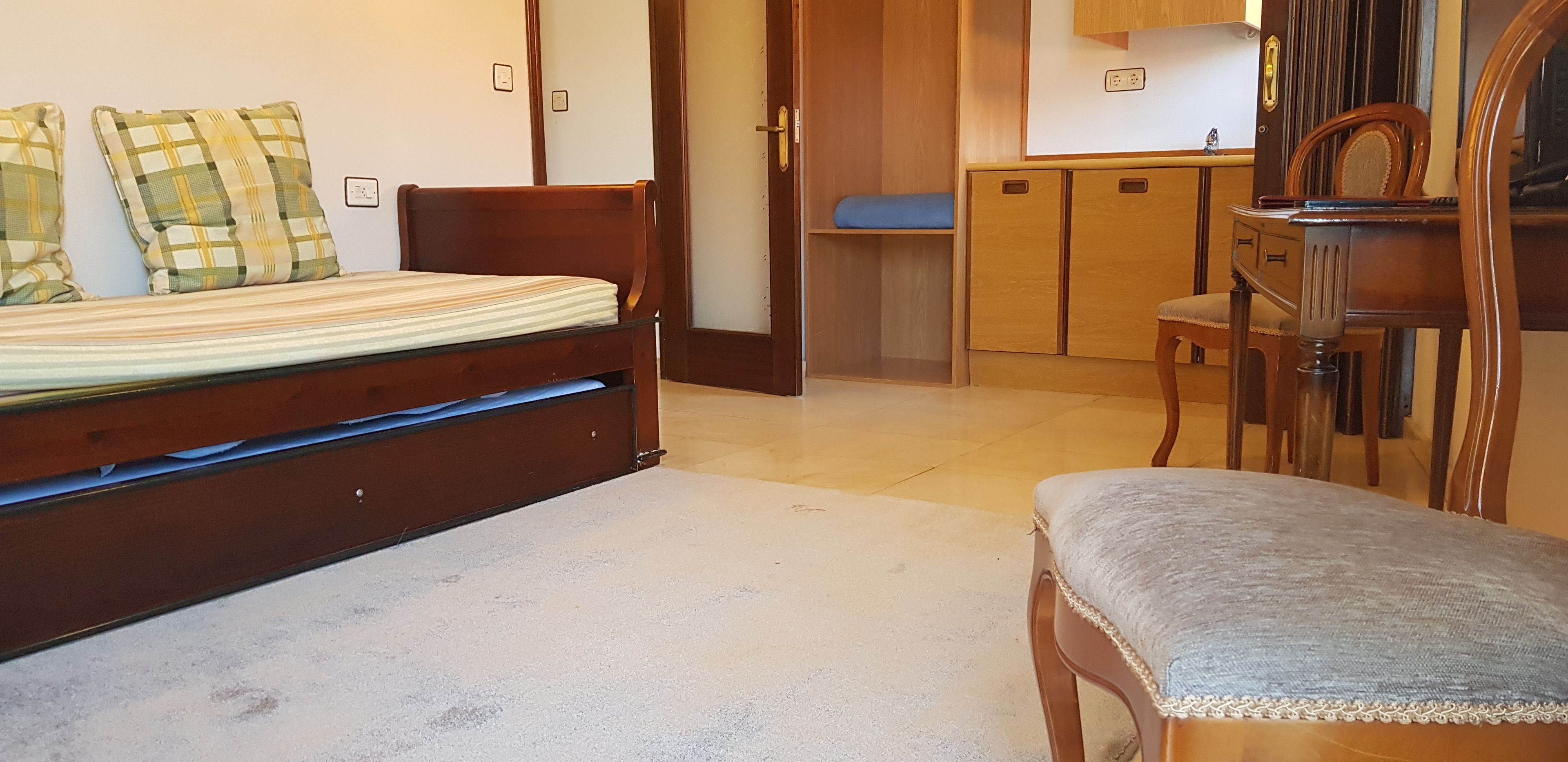 A bedroom with a bed, a chair, a desk, and a wardrobe.