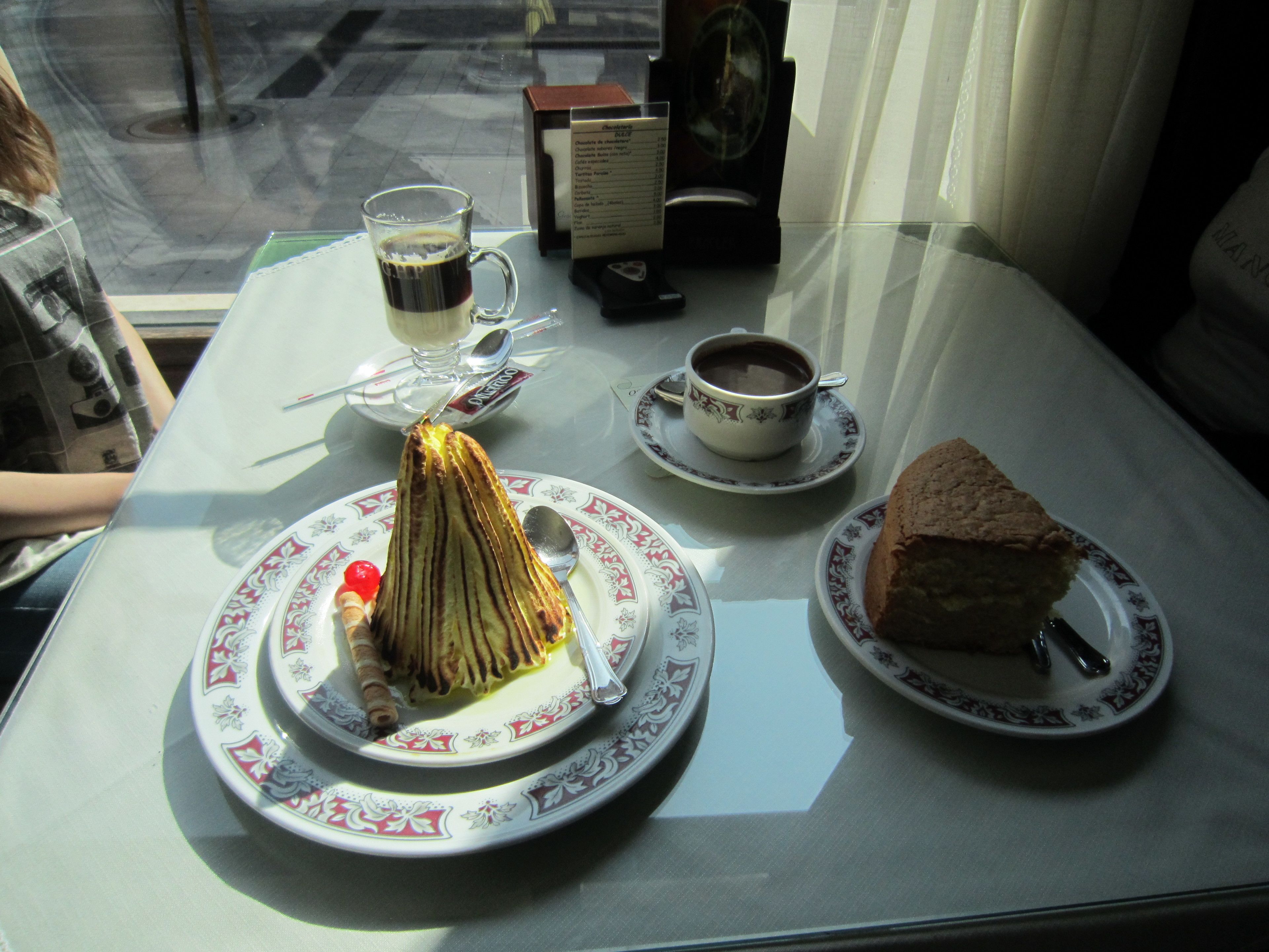 A table with a dessert, a cup of coffee, and a menu.